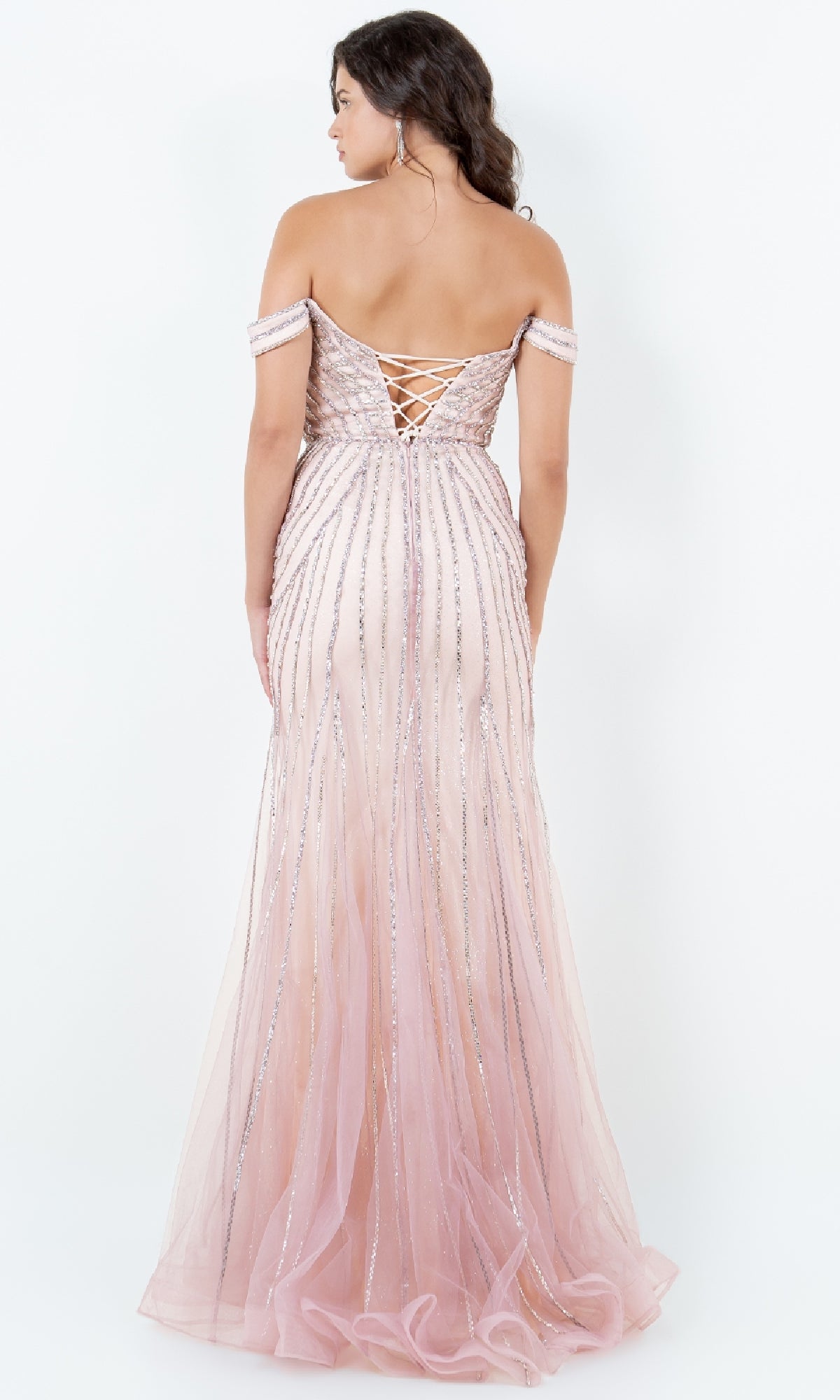 A woman stands facing away in the Cinderella Couture 8271J, a long beaded prom dress with an off-the-shoulder pink design, lace-up back, and silver sequin stripes.